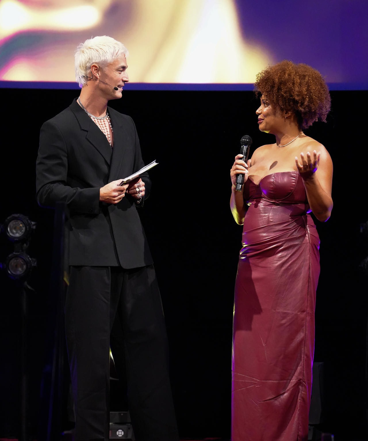 Robin-April met microfoon op het podium tijdens een award show